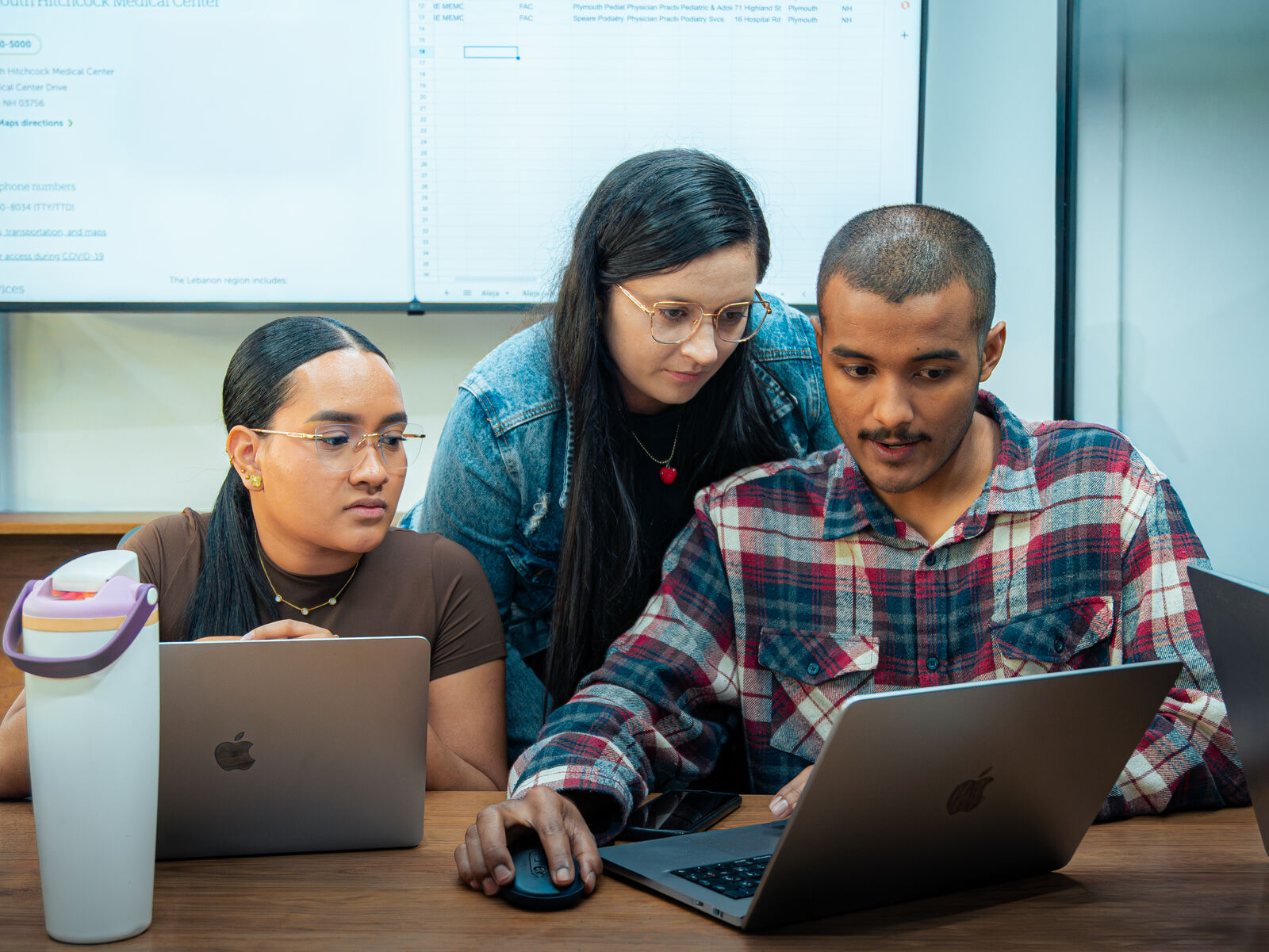 Three engineers reviewing a healthcare dataset together on a laptop.
