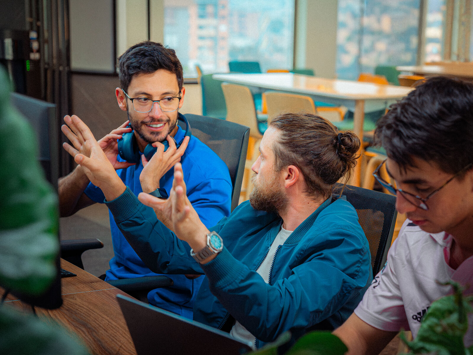 Engineers in an animated technical discussion at their desks.
